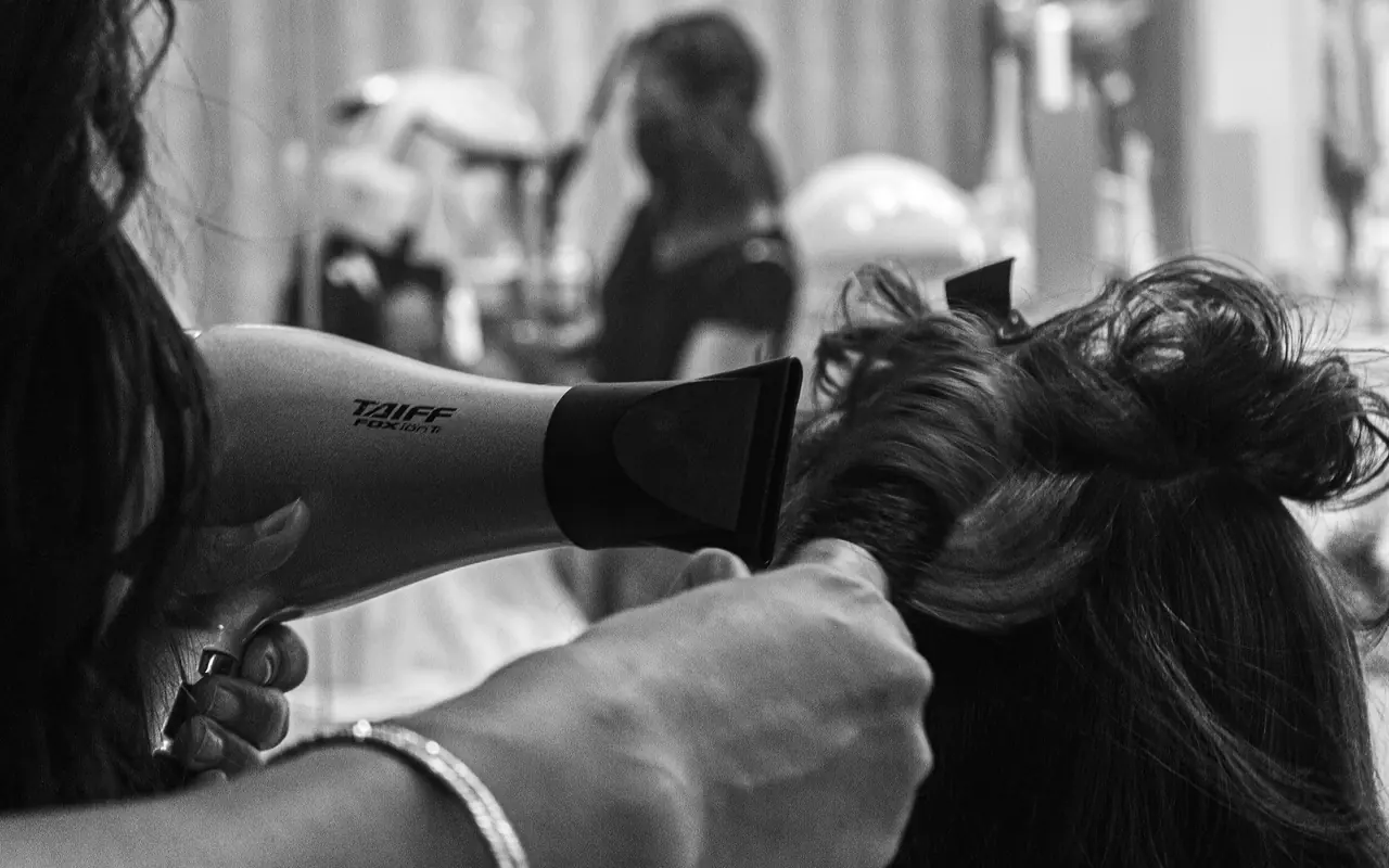A stylist blow-drying a client’s hair in a salon