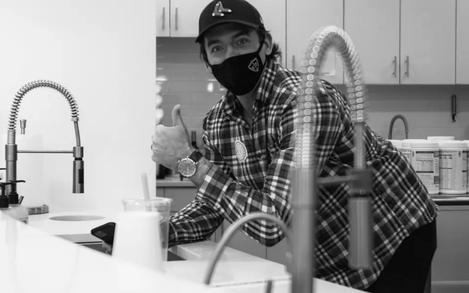 A technician fitting a new faucet at a kitchen sink