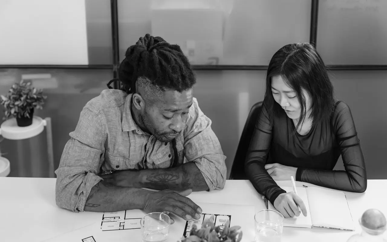 Two people reviewing property floor plans together at a table